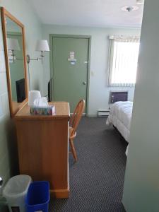 a hotel room with a bed and a desk with a mirror at Chimo Motel in Cochrane