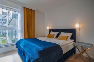 ein Schlafzimmer mit einem Bett mit einer blauen Decke und einem Fenster in der Unterkunft CITYSTAY Św.Barbary Apartment in Danzig