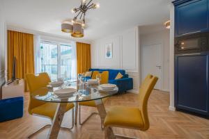 ein Esszimmer mit einem Glastisch und gelben Stühlen in der Unterkunft CITYSTAY Św.Barbary Apartment in Danzig