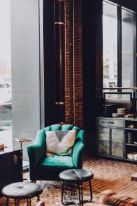 a living room with a green chair and two stools at Crossroads Hotel in Kansas City
