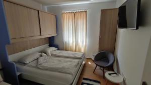 um pequeno quarto com uma cama e uma cadeira em B&B Isola em Izola