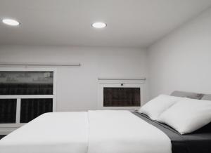 biała sypialnia z łóżkiem i 2 oknami w obiekcie HomeForGuest BIOMA Modern & Minimalist Apartment w mieście Santa Cruz de Tenerife