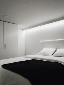 biała sypialnia z łóżkiem z czarnym kocem w obiekcie HomeForGuest BIOMA Modern & Minimalist Apartment w mieście Santa Cruz de Tenerife