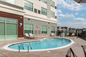 a swimming pool with chairs and a building at Cambria Hotel Fort Mill in Fort Mill