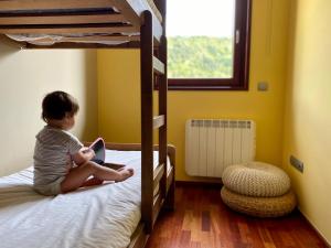 a young child sitting on a bed reading a book at Apartaments Turístics Cal Patoi in Martinet