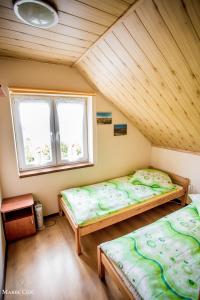 two beds in a room with a wooden ceiling at Domki u Strażaka obiekt Całoroczny in Solina