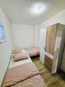 - une petite chambre avec 2 lits et une armoire en bois dans l'établissement Apartman Školj, à Jovići