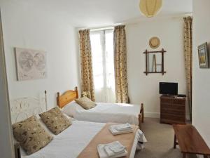 a bedroom with two beds and a table and a tv at Maison de Fortitude Chambres d'hotes in Salviac