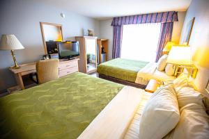 a bedroom with a bed, desk, chair, and lamp at Ocean Paradise Hotel & Resort in Ocean Shores