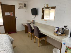 a room with a desk with two chairs and a bed at Orana Motor Inn in Mildura