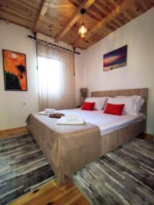 a bedroom with a large bed with red pillows at Cottage Ajna - Ada Bojana in Ulcinj