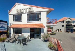 a motel with chairs and a table in front of it at Panorama Motor Lodge in Timaru