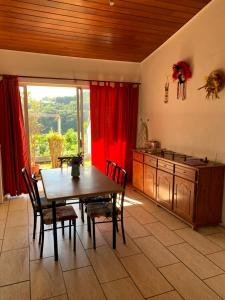 une cuisine avec une table en bois et un rideau rouge dans l'établissement Wendy Location, à Papeete