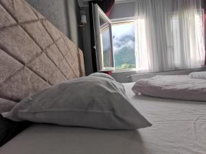 Cama con almohada en habitación con ventana en Hotel Rosi en Gusinje