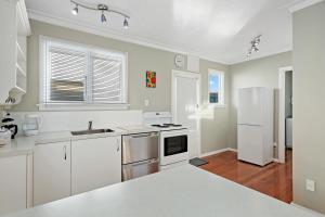a kitchen with white cabinets and a white refrigerator at Coastal City Retreat - New Brighton Accommodation in Christchurch