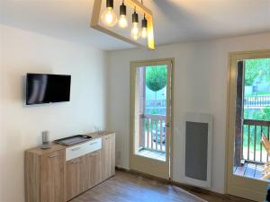 sala de estar con TV y 2 ventanas en Le cozy du soulan - T2 bis - soda en Luchon