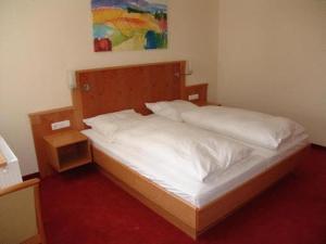 1 dormitorio con 1 cama con sábanas blancas y una pintura en Hotel Pension Futterknecht en Burgau