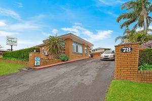 a house with a car parked in front of a driveway at Sandpiper Motel Ulladulla in Ulladulla