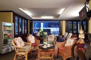 a living room with chairs and a couch and windows at People Place Classic Hotel SHA Extra Plus in Chiang Mai