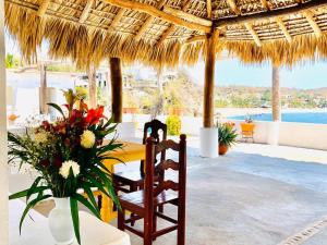 a dining table and chairs under a thatched umbrella at Hotel Cordelia's in Puerto &Aacute;ngel