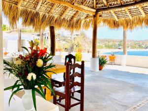 mesa de comedor y sillas bajo una sombrilla de paja en Hotel Cordelia's en Puerto Ángel