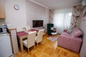 een keuken en een woonkamer met een tafel en een bank bij Apartman Boska in Subotica