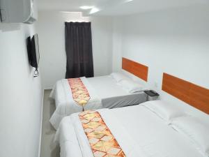 a bedroom with two beds and a television in it at Orange Villa Hotel Near Palm Mall Seremban in Seremban