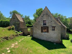 een oud stenen huis met een raam en een tuin bij Gîte - Le Reclaud du Noyer in Le Bugue