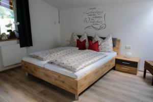 1 dormitorio con cama de madera y almohadas rojas en Ferienwohnungen Hechenblaikner en Maurach