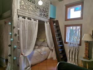a room with a bunk bed with curtains and a ladder at Le gite de Coco in Riquewihr