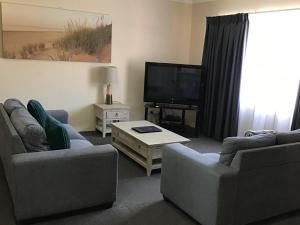 a living room filled with furniture and a tv at Sandcastles Holiday Apartments in Coffs Harbour