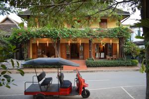 a golf cart with chairs and an umbrella in front of a building at Sala Prabang Hotel in Luang Prabang