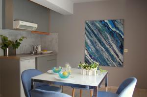 cocina con mesa blanca y sillas azules en ALKYONI Studios Poros Kefalonia en Póros Kefalonias