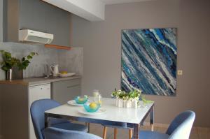a kitchen with a white table and blue chairs at Alkyoni Apartments & Studios in Poros
