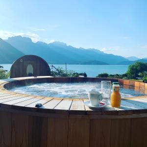 een hot tub met een drankje en een glas sinaasappelsap bij Hôtel Beauregard, The Originals Relais (Inter-Hotel) in Sévrier