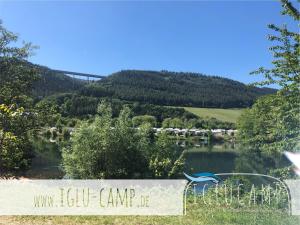 um sinal em frente a um lago com uma ponte ao fundo em Iglu Camp Triolago em Riol