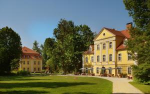 a large yellow building with a lawn in front of it at Pałac Łomnica Karkonosze - Schloss Lomnitz Riesengebirge in Jelenia Góra