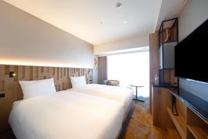 a hotel room with two beds and a flat screen tv at Miyako City Osaka Hommachi in Osaka