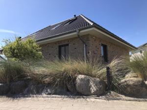 a brick house with some tall grass and rocks at Ferienwohnung Böverdün in Sankt Peter-Ording
