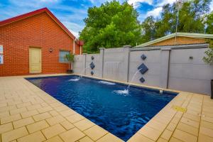 a swimming pool with a fence and water fountain at Murray Waters Motor Inn & Apartments in Koondrook
