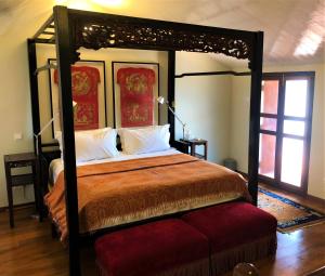 a bedroom with a canopy bed with a red ottoman at Seven Terraces in George Town