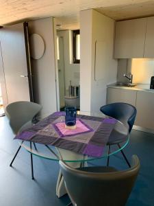 uma mesa de vidro com cadeiras e uma bebida em House of retreat Strada Vegia de Brén 9 em Breno
