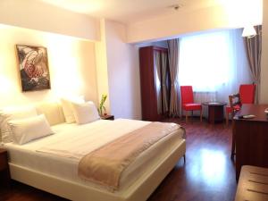 um quarto de hotel com uma grande cama branca num quarto em Atrium Hotel Bucharest City Center em Bucareste