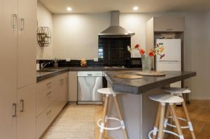 a kitchen with white cabinets and a counter with stools at Lake Escape in Queenstown
