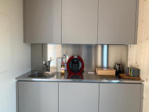 uma cozinha com armários brancos e um aparelho vermelho no balcão em House of retreat Strada Vegia de Brén 9 em Breno