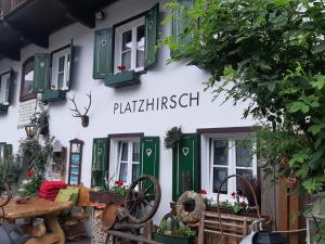 a white building with green windows and a sign on it at Platzhirsch zur alten Wagnerei in St. Wolfgang