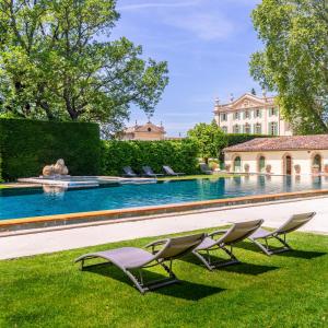 a group of chairs sitting in the grass next to a swimming pool at Chateau de Tourreau in Sarrians