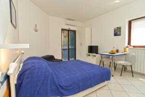 a bedroom with a bed with a blue comforter and a table at Apartments Stana 242 in Fažana