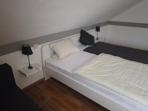 Hotel Waldterrasse في Rengsdorf: غرفة نوم صغيرة بها سرير أبيض ومصباحين
