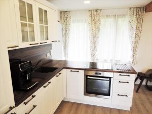 a kitchen with white cabinets and a sink and a microwave at Auszeithäuserl in Oberhaag